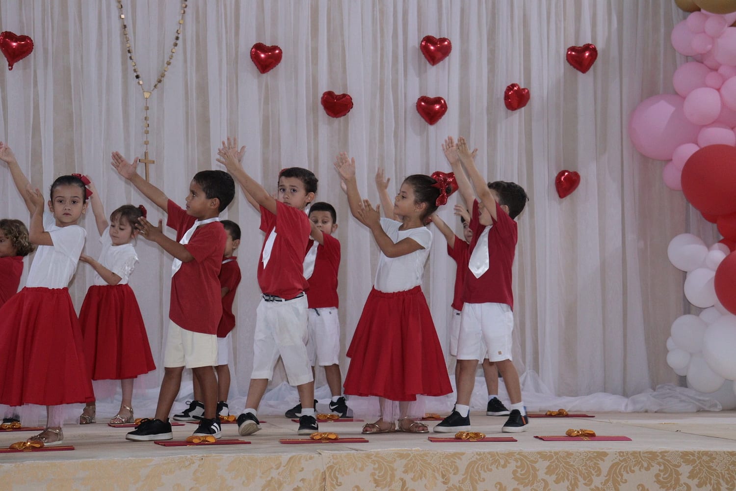 Crianças de vermelho e branco dançando no palco