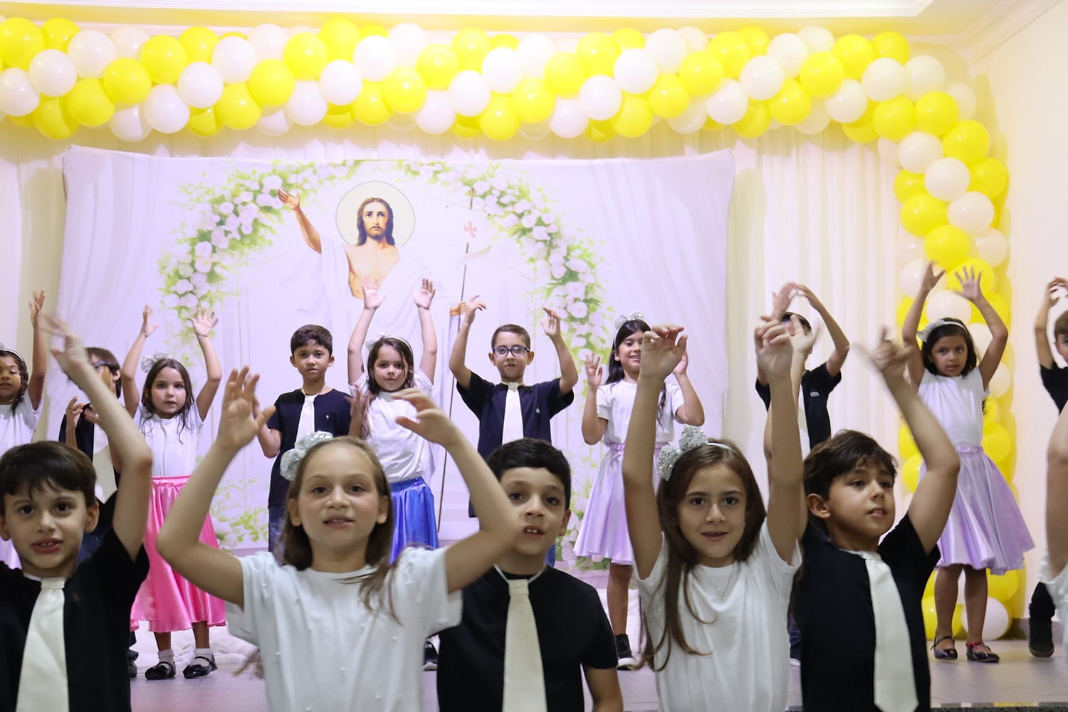 Alunos de braços erguidos numa apresentação no palco