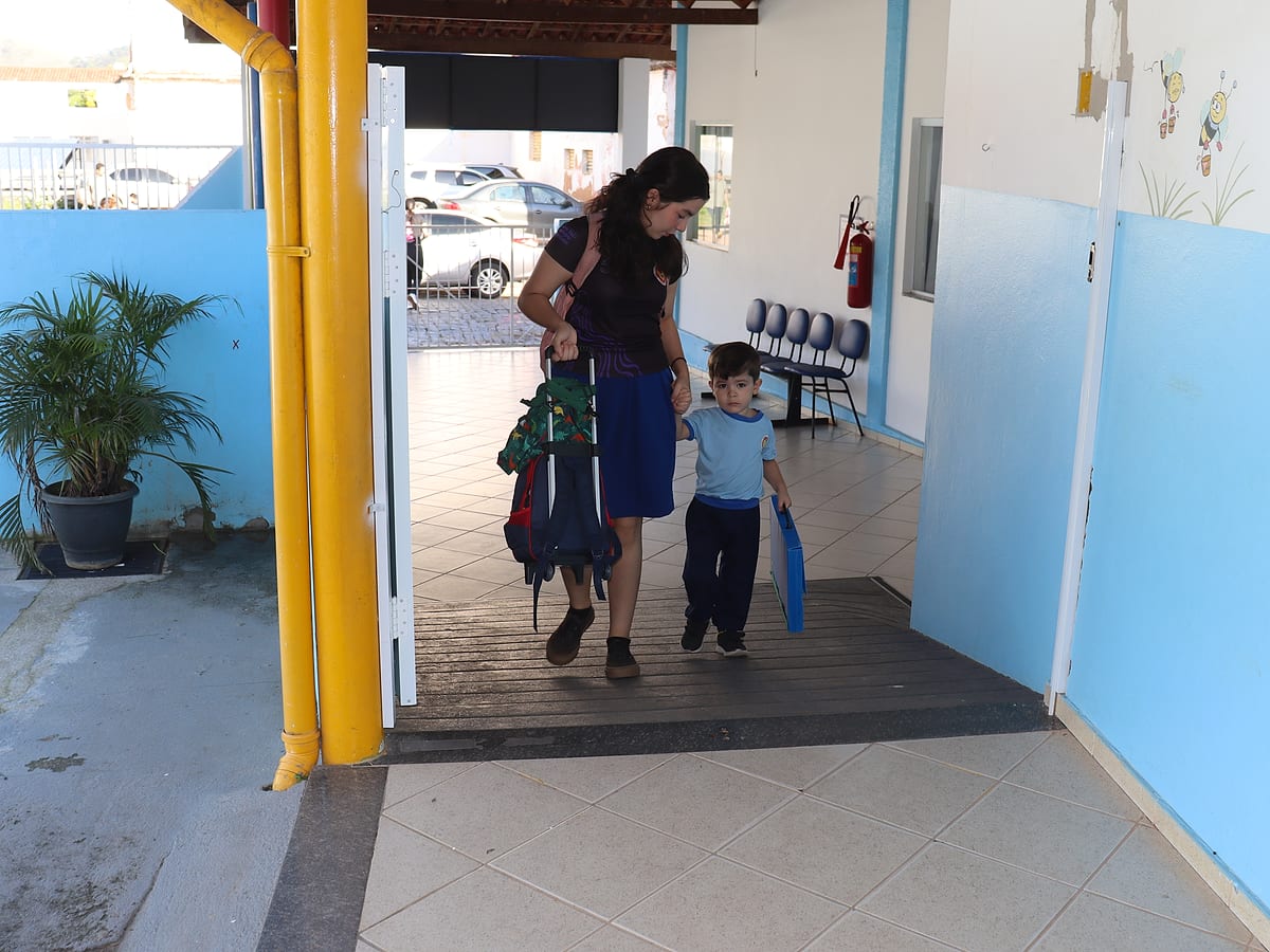 Mãe e filho chegando de mãos dadas à Educação Infantil